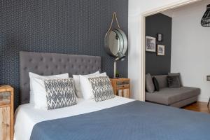 ein Schlafzimmer mit einem Bett, einem Stuhl und einem Spiegel in der Unterkunft DuMont Lisbon Guesthouse in Lissabon