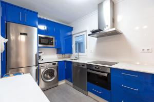 uma cozinha com armários azuis e uma máquina de lavar e secar roupa em Apartamento en Santoña em Santoña
