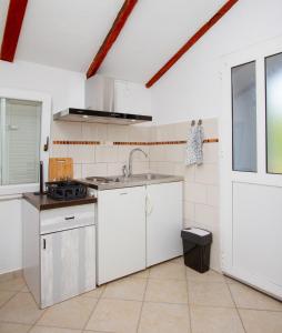 uma cozinha com armários brancos e um lavatório em Sole e Limone em Kraj