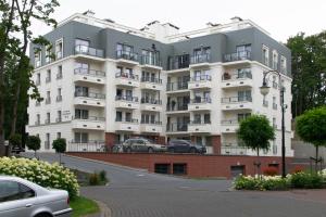 un gran edificio blanco con coches estacionados frente a él en Apartment Kaisermöwe, en Świnoujście