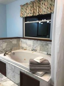 a bathroom with a tub and a window and towels at Hawaii Tropical Volcano mansion + Sauna in Hilo