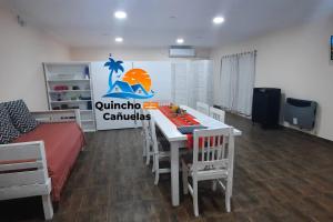 Un comedor con una mesa y sillas y una cama. en Quincho 23 Cañuelas, en Cañuelas