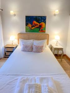 a bedroom with a large white bed with two lamps at La Infinita Rural Boutique in Carmona