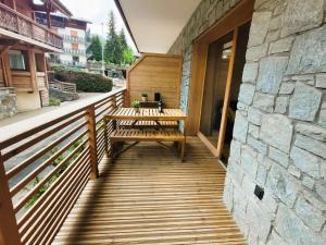 a wooden deck with benches and a stone wall at Appartement neuf au centre des Gets avec balcon, sauna, parking et proximité pistes - FR-1-598-138 in Les Gets