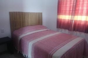 a small bedroom with a bed and two windows at Bungalow en la mejor ruta turística de Oaxaca in San Jerónimo Tlacochahuaya