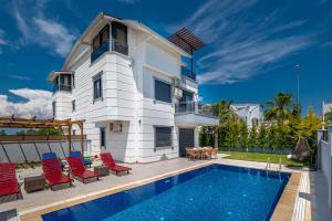 Villa w Jacuzzi, Private Pool, Garden in Antalya في بيليك: منزل به مسبح وكراسي حمراء
