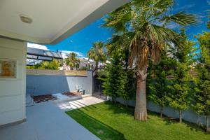 Villa w Jacuzzi, Private Pool, Garden in Antalya في بيليك: نخلة في الحديقة الخلفية للمنزل