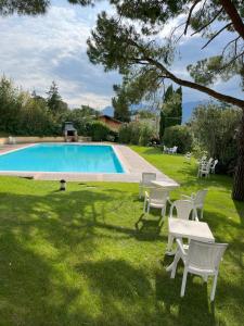 a pool with chairs and a table in the grass at Apartment Claudia Malcesine in Malcesine