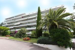 duży apartamentowiec z palmami i roślinami w obiekcie Mathéo w Cannes