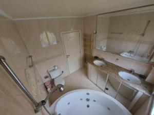 a bathroom with a tub and two sinks and a toilet at Adromeda Aegean Sea View villa in Koskinou