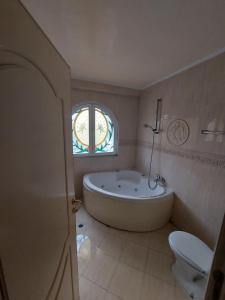 a bathroom with a tub and a toilet and a window at Adromeda Aegean Sea View villa in Koskinou