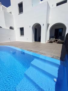 a villa with a swimming pool and white walls at Amphitrite Suites Santorini in Vóthon