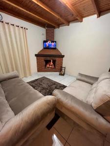 a living room with two couches and a fireplace at Chacara Recanto dos Pássaros in Camanducaia +25 photos