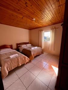 two beds in a room with a wooden ceiling at Chacara Recanto dos Pássaros in Camanducaia