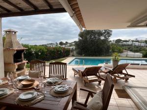 a dining table and chairs on a patio with a pool at Vila Rosa - Private Swimming Pool With Sea View in Albufeira