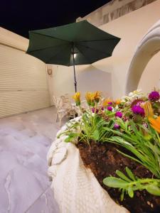 a garden with a green umbrella and flowers at بيت النرجس الخاص in Riyadh