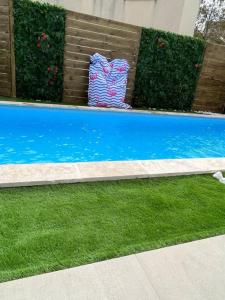 een blauw zwembad met groen gras en struiken bij Villa La caroline 2 in Montpellier