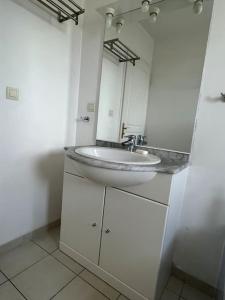 een witte badkamer met een wastafel en een spiegel bij Villa La caroline 2 in Montpellier