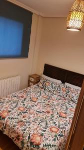 a bed with a floral comforter in a bedroom at Cristo22 Apartamento recién reformado con parking propio in Vigo