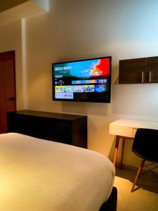 a hotel room with a bed and a flat screen tv at Villa Anahata in Porlamar