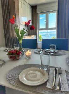 a table with a white plate and a vase with red flowers at Luxury and Spa App F in Makarska