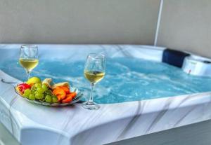 two glasses of wine and a bowl of fruit in a swimming pool at Luxury and Spa App F in Makarska