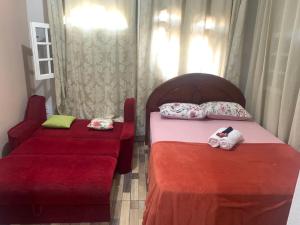 um quarto com 2 camas com lençóis vermelhos e uma cadeira em Apto Amar - No Espaço Florescer em Campos dos Goytacazes