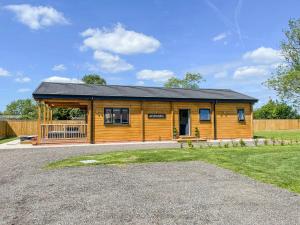 a large wooden cabin with a porch in a yard at Aylesbury Lodge in Halstead