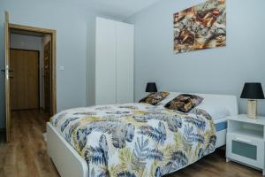 Schlafzimmer mit einem Bett mit einer blauen und weißen Bettdecke in der Unterkunft Modern Apartments in center of Katowice in Kattowitz