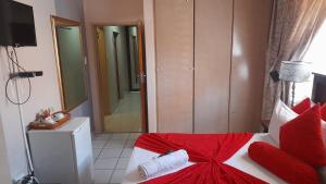 a bedroom with a red and white bed and a bathroom at Umqhele Guest Lodge in Richards Bay