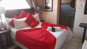een groot bed met rode en witte kussens erop bij Umqhele BnB in Richards Bay