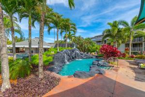 a resort pool with a waterfall and palm trees at Beautiful Princeville Garden Condo with lots of Amenities C2108 in Princeville