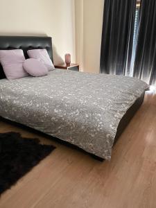 - un lit avec une couette et des oreillers gris dans une chambre dans l'établissement Apartamento Alcochete, à Alcochete
