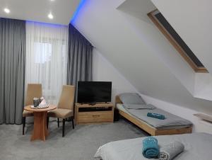 Cette chambre comprend un lit, une télévision et une table. dans l'établissement Motelik Zajazd u Marcela, à Bysław