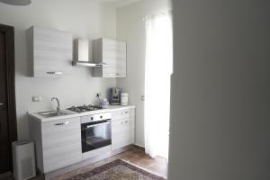 uma cozinha com armários brancos e um forno com placa de fogão em Casa delle Macine em Caltanissetta