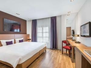 a hotel room with a large bed and a desk at Mercure Hanoi La Gare Hotel in Hanoi