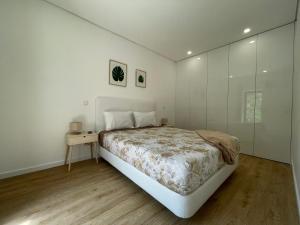a white bedroom with a large bed and a table at Teixeira Home - Gerês in Geres