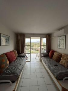 uma sala de estar com 2 sofás e uma varanda em Appartement Village Vacances Cap Esterel em Saint-Raphaël