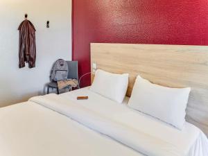 a bedroom with a white bed with a red wall at hotelF1 Paris Porte de Châtillon in Paris