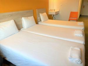 two beds in a hotel room with white sheets at hotelF1 Paris Porte de Châtillon in Paris