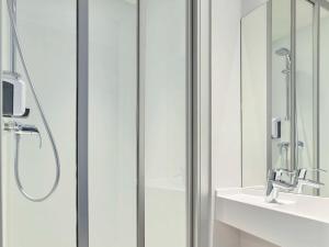 a bathroom with a shower and a sink and a mirror at hotelF1 Paris Porte de Châtillon in Paris