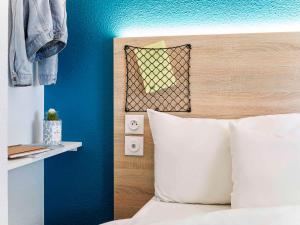 a bedroom with blue walls and a bed with white pillows at hotelF1 Paris Porte de Châtillon in Paris