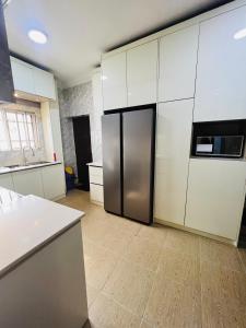 a kitchen with a stainless steel refrigerator and white cabinets at House Ire in Abuja