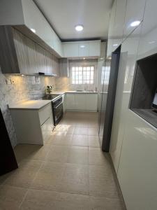 a kitchen with white cabinets and a tile floor at House Ire in Abuja