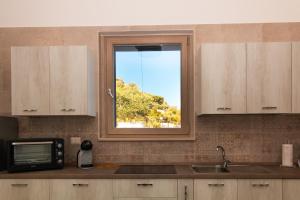 a kitchen with a window over a sink and a microwave at Villa Terrazza sul Golfo in Monte SantʼAngelo