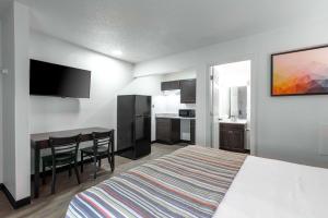 a hotel room with a bed and a table and a kitchen at Suburban Studios in Spartanburg