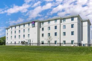 un gran edificio blanco con un campo de césped delante de él en MainStay Suites North - Central York en York