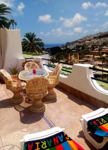 a patio with a table and chairs on a balcony at Most sunny days on Gran Canaria in Puerto Rico de Gran Canaria