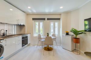 a kitchen with white cabinets and a table and chairs at Bonneville Setúbal II in Setúbal