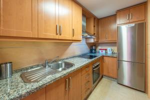 a kitchen with wooden cabinets and a stainless steel refrigerator at Apartamento Punta del Faro in Torrox Costa